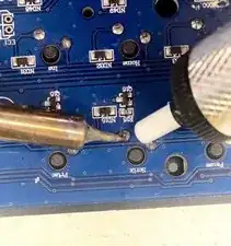 Using soldering iron touch its tip to the pin and when it melts press pump on it and push the button. Th pump should suck all the melted solder, if it failed try again