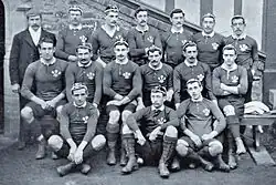 Three rows of rugby players wearing their playing uniforms and caps