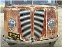Front end with grill, emblem, and teardrop headlights