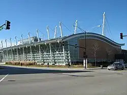 Ground-level view diagonally across an intersection of a building with several tall white poles