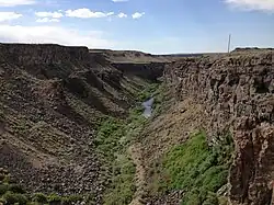 A small stream flowing through an arid, steep-sided canyon