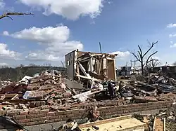 A damaged home amidst a pile of rubble and a blue sky.