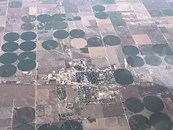 Aerial image of a small American town laid out on a grid, on a flat plain surrounded by irrigated fields