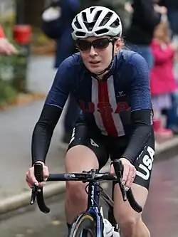 Emily Ehrlich riding a bicycle, wearing a USA cycling jersey