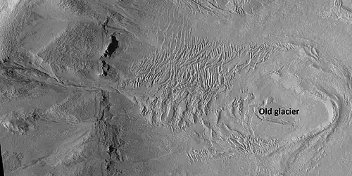 Glacier on a crater floor, as seen by HiRISE under HiWish program. The cracks in the glacier may be crevasses. There is also a gully system on the crater wall.