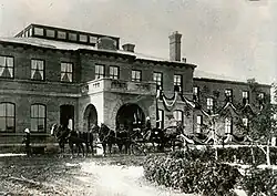 A sepia photograph of the Government House during the Royal Visit. A horse-drawn carriage is in front of the building.