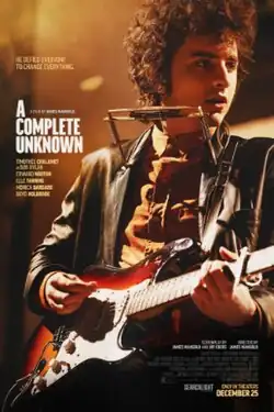 Bob Dylan (portrayed by Timothée Chalamet) performs with an electric guitar equipped with a harmonica holder.