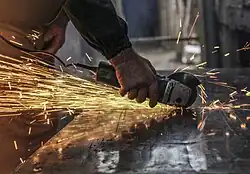 Bright sparks fly as a man grinds a piece of metal