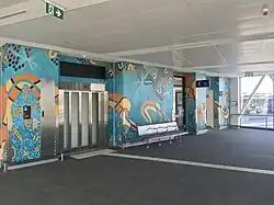 Lift entrance with teal and orange painted artwork along the wall