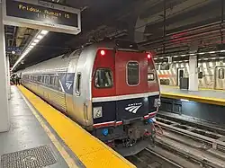 A silver railroad car with a blue stripe over the windows. At one end, an angular green shape covers the stripe.