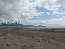 Wide flat beach with snow-capped mountains in the background
