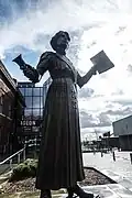 Annie Kenney's statue in Oldham with a copy of Votes for Women