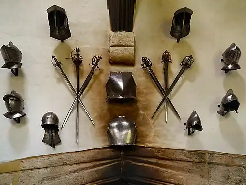 collection of armoured helmets and weapons, wall-mounted