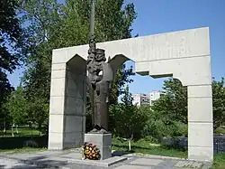 A bearded man wearing a crown and holding a long sword in his right arm right above his shoulder