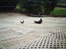 Photograph of the dry ski slope at the Mendip Snowsport Centre with two people tobogganing down the slope