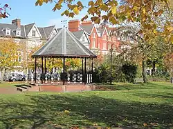 a bandstand in a park (temple gardens), with houses in the background
