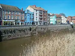 Three and four-storey buildings on the far side of a river.