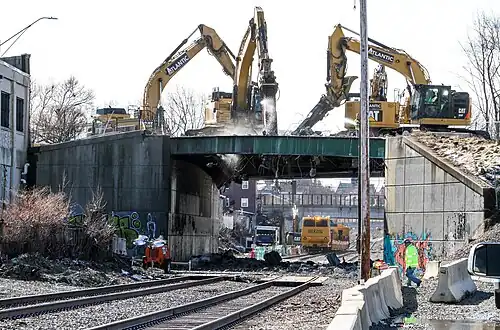 A bridge being demolished by four excavators