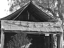 Fig. 9: The northern gable-end was fashioned by nailing sheets of galvanized iron onto a sub-frame. Insecurely fastened to the main structure, it has fallen out.