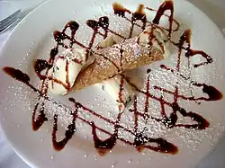 A cannoli with a chocolate sauce decoration