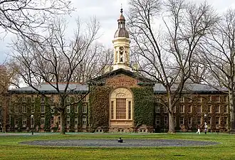 A Renaissance brick building with green shrubbery and a large white spire