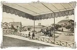 A beachfront illustration from a perspective under an ornate canopy; in the distance are other buildings, small sand dunes, and boats, while in the foreground are men in suits with top hats, women in broad dresses, and children playing