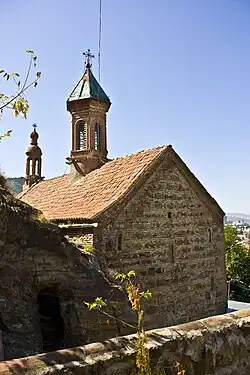 The view of the church from the inner garden. Over the pass, cut in the rock, Bolnisi Cross can be seen..