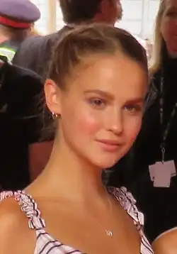 Blurry image of Clara Rugaard wearing patterned dress with shoulder straps, looking slightly left of camera