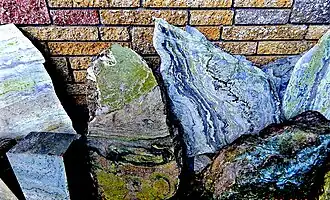 An image of some slabs of connemara marble against a wall. Each slab has coloured swirls, the middle one stands out because the entire slab is moss green in colour.
