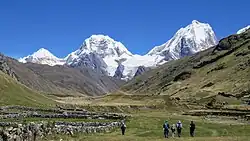Snow-covered peaks under a clear sky with hikers in the foreground