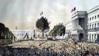 Lithographie colorée représentant les décorations de la place des Palais à l'occasion des 25 ans de l'inauguration de sa majesté le Roi Léopold Ier. Une foule de belges se tient devant le Palais royal.