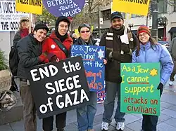 group of people at a protest holding signs like "End the siege in Gaza"