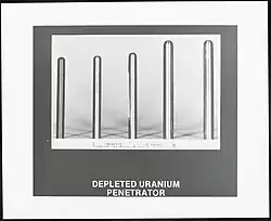 A photographic print of five vertically oriented uranium penetrator rods arranged left to right from shortest to longest. The scale measurement at the bottom shows the width of the rods also increasing in width from left to right from a quarter of an inch to almost half an inch.