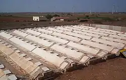 The condenser at Satapar in India consists of eleven ridges. The ridges are trapezoidal in section (top 50 cm, base 200 cm, two sides sloping 30-degree from horizontal, height 100 cm) and each is 20 m long. The ridges are built over gently sloping ground. All the ridges drain into a common pipe at the lower and leading to storage below ground. Water for use is withdrawn by a hand pump. The system was commissioned in early April 2007. Total cost of the installation was Rs 117,000.