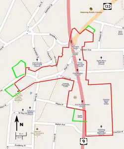 A map of the streets in downtown Ossining, on a gray background with major roads in pink and orange and the locations of some landmarks indicated. The border of the irregularly-shaped historic district is in red. Four small green-bordered areas are adjacent to it.