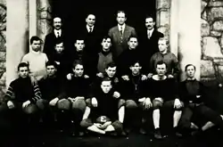 An old black and white photograph of eighteen male student members dressed in football gear