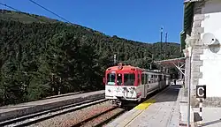 A train in a station (cotos). They are painted red and white