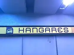 Picture of a wall sign featuring Hangares logo, a biplane inside a hangar.