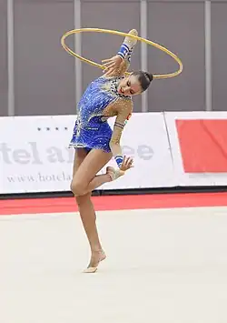Kanaeva revolves a hoop around her bent elbow