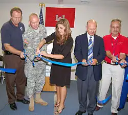 Five people cutting a blue ribbon.
