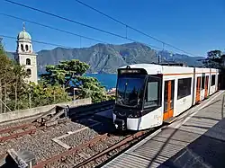 Low-floor tram at railway station overlooking a lake