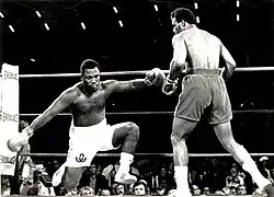 Foreman standing over Frazier during the second round