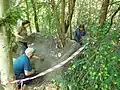 Staff and volunteers smoothing surface of mud sofa, a temporary barrier of local material