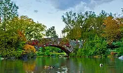 A stone bridge above a lake, with autumn foliage on either side