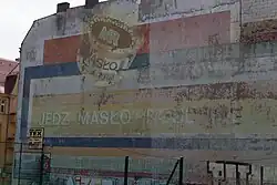 Ghost sign for MR Masło, a butter brand, in Poznań, Poland. The caption reads "Eat plant butter"
