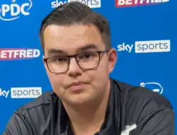 Gian van Veen at a 2025 World Matchplay press conference, sitting in front of a panel with logos.