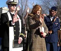 A white man in uniform, a white woman, and a Black woman in uniform, standing outdoors, eyes closed and hands raised in prayer