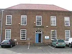 Redbrick Georgian style building with pan tiled roof and nine multi paned high windows complemented by an arched entrance doorway giving symmetrical architectural spacing to the facade