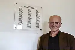 Hans Joachim Lang in front of the plaque in memory of 86 Jews killed in August 1943 in the gas chamber of Natzweiler-Struthof concentration camp.