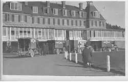 Black-and-white photo of old ambulances next to a building
